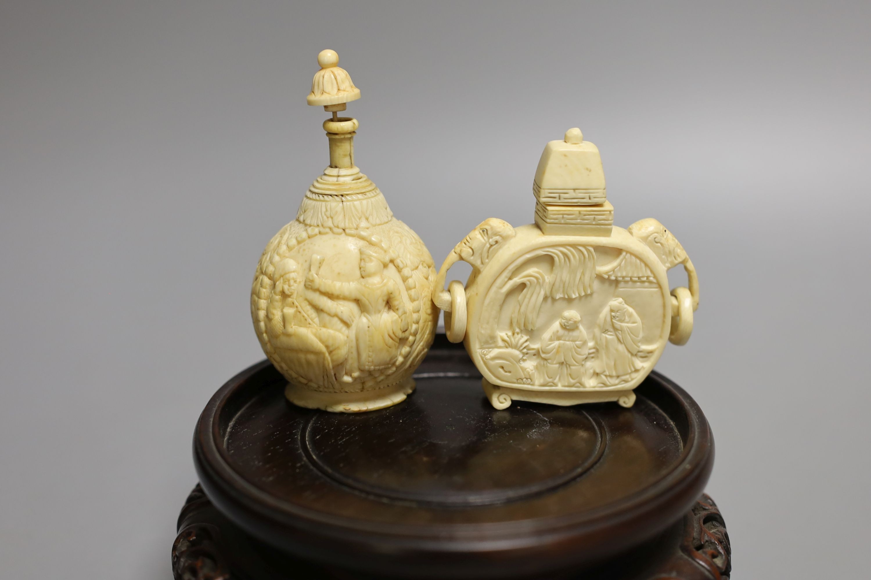 A 19th-century European carved ivory snuff bottle, and an early 20th century Chinese ivory snuff bottle and an ivory Netsuke of a lion-dog and a Chinese hongmu stand (4)